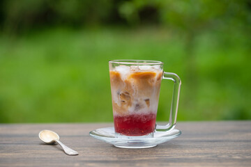 Refreshing raspberry milk iced coffee on a summer day in the garden, close up