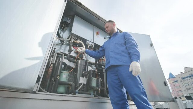 The technician checking power lines of the heat exchanger with current clamps