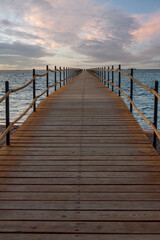 Obraz premium Wooden pier extending into the sea at sunrise