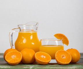 Fresh orange juice in clear jar and glass decorating with fresh orange on colourful wooden table. Studio picture concept for healthy diet. Studio picture