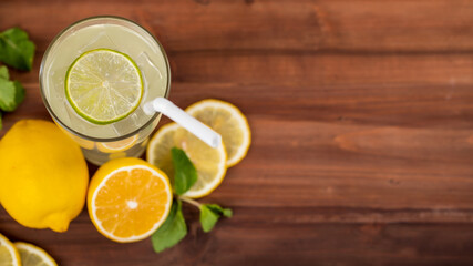 A refreshing glass of cold lime juice with ice and straw, decorating the glasses with lime slice. Fresh lime, lemon both cut and slice and mint leaf are on wooden table. Healthy concept © Bangkok Click Studio