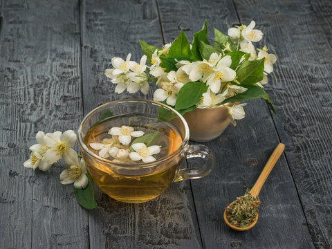 Jasmine flowers and flower tea in a glass bowl on a wooden table.