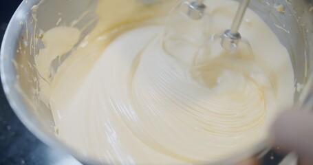 close up automatic flour mixing machine mixing delicious cream to make cake. ingredient of cake is egg, butter and sugar in the bowl, making bakery	
