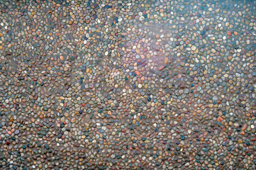 Transparent water flows down the pebbles. Pebble or gravel background or texture.