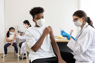 young male african wearing medical face mask and getting vaccinated from doctor, to build up or maintain immunity