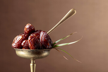 Sweet dried dates in a brass dish.