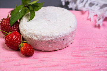 Camembert with strawberries with mint on a pink wooden board on a grey background 