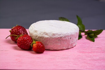 Camembert with strawberries with mint on a pink wooden board on a grey background 
