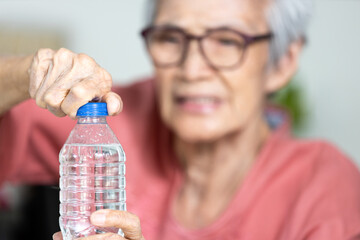 Trouble opening the bottle of drinking water in the elderly age,life problem,senior woman with numbness and weakness of hands and fingers muscle,difficulty in turning or unscrewing cap of water bottle