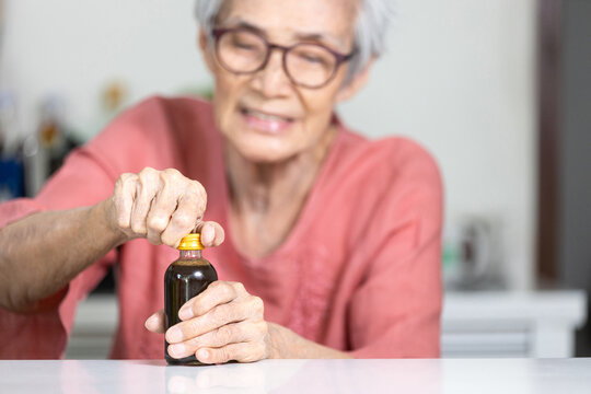 Trouble opening the lid of the bottle in the elderly aged,fingers without strength and weak,senior woman trying hard to open the screw cap,problem of hand weakness or wrist pain,numbness in the hands
