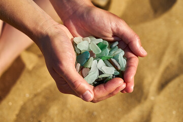 Cupped hands hold sea glass collected from the beach
