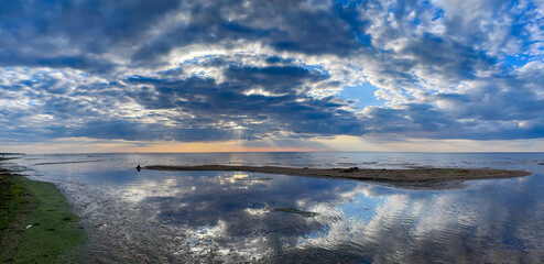 Obraz premium Panorama of the warm Gulf of Riga of the Baltic Sea against the background of cumulus clouds at sunset. The coast of the Gulf of Riga in Latvia is popular with tourists.
