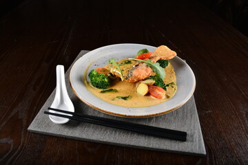 deep fried salmon fish with golden salted egg yolk sauce and vegetables seafood in dark background asian halal menu