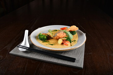 deep fried salmon fish with golden salted egg yolk sauce and vegetables seafood in dark background asian halal menu