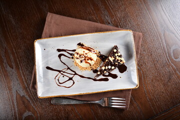 dark chocolate brownie with vanilla ice cream dessert with peanut and chocolate sauce on plate in dark background western halal menu