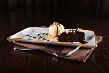 dark chocolate brownie with vanilla ice cream dessert with peanut and chocolate sauce on plate in dark background western halal menu