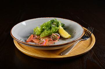 smoked salmon fish with vegetables, lemon and salad dressing appetiser in dark background western halal menu
