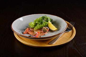 smoked salmon fish with vegetables, lemon and salad dressing appetiser in dark background western halal menu