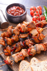 Board with tasty chicken kebab on dark wooden background