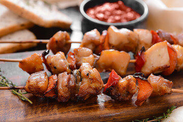 Board with tasty chicken kebab on dark wooden background
