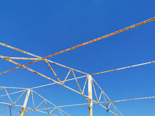 an angular drawing of a structure made of old rusty peeling white pipes and beams against the background of a clear blue sky