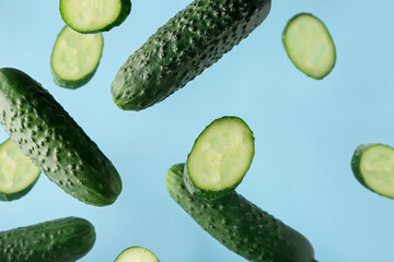 Flying cucumbers on color background