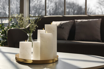 Tray with candles and flowers on table in living room