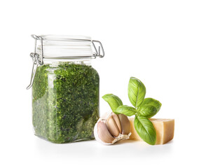 Jar with fresh pesto sauce and ingredients on white background