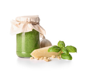 Jar with fresh pesto sauce and ingredients on white background