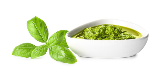 Bowl with fresh pesto sauce and basil leaves on white background