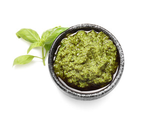 Bowl with fresh pesto sauce and basil leaves on white background