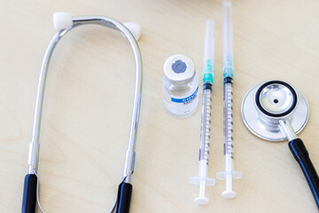 Vaccination concept and medicine: syringe with coronavirus vaccine and disposable vaccination device. Medical device stethoscope to treat flu, coviral-19 virus epidemic.