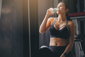 Happiness woman in sportswear drinking protein powder milkshake after workout at fitness gym. - obrazy, fototapety, plakaty