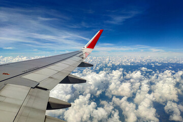 Fototapeta na wymiar Aircraft wing through window with clouds and horizon background.
