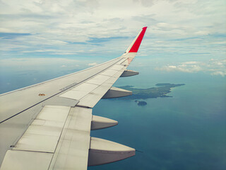 Aircraft wing through window with ocean background.