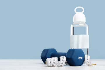 Blue 2 kg dumbbell and measuring tape. Glass water bottle. Workout and exercise fitness weight...