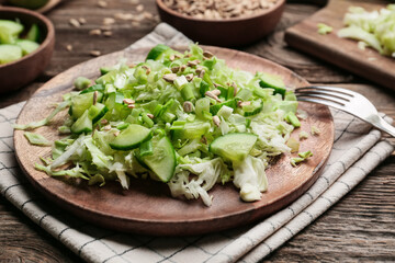 Plate with tasty cabbage salad on wooden table