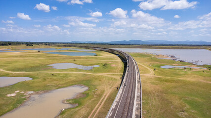 Aerial Unseen view of railroad tracks of floating Train bridge with white car in Khok Salung, Pa Sak Jolasid dam Lopburi amazing Thailand, Known as a floating train route.