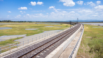 Aerial Unseen view of railroad tracks of floating Train bridge with white car in Khok Salung, Pa Sak Jolasid dam Lopburi amazing Thailand, Known as a floating train route.
