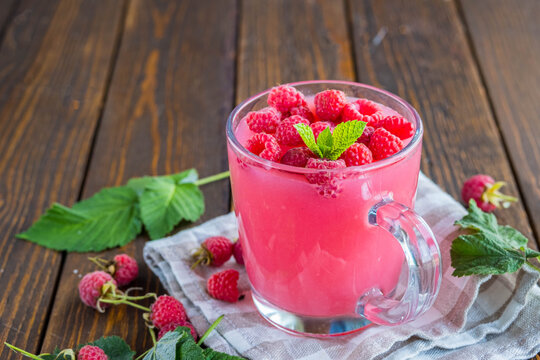 Traditional Russian hot drink raspberry jelly or kissel in a glass transparent mug on a brown wooden background.