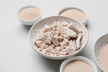 Bowls with fresh and dry yeast on light background