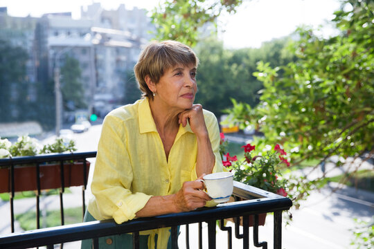 Senior woman drinking coffee on the balcony of his apartment