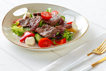 Fillet of beef with vegetable salad on wooden table