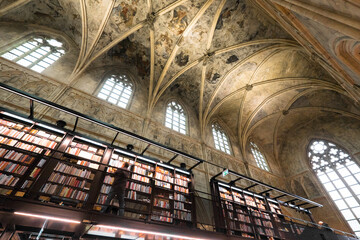 Interior of Dominican church converted into a bookstore with restaurant, customers, cathedral ceilings and pillars of the church in Maastricht, Netherlands - obrazy, fototapety, plakaty