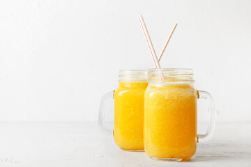 Mason jars of tasty pineapple smoothie on white background