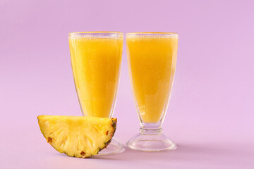 Glasses of tasty pineapple smoothie on color background