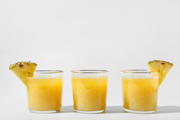 Glasses of tasty pineapple smoothie on white background