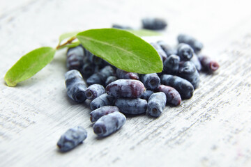 Honeysuckle (Lonicera caerulea) berries and fresh leaves on grey wooden table
