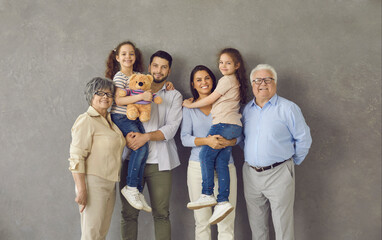 Studio photo shoot group portrait of cheerful big extended multi generational family against grey...