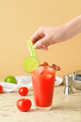 Woman decorating bloody mary cocktail on color background © Pixel-Shot